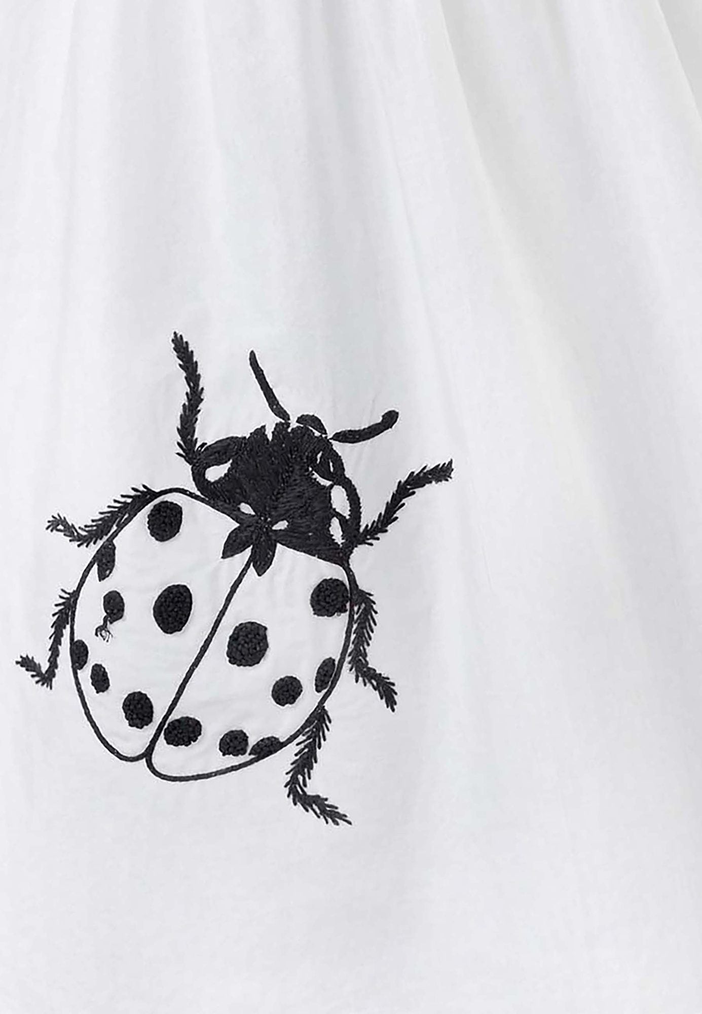 Witte jurk met uitgesneden rug en lieveheersbeestje handborduurwerk